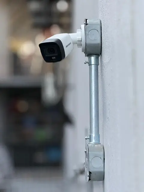 Cámara tipo bala Hikvision instalada en pared exterior con tubería galvanizada