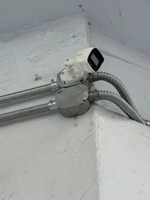 Cámara Hikvision instalada en esquina con canalización eléctrica protegida
