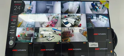 Monitor con 16 cámaras Hikvision mostrando bodega, tienda y estacionamiento