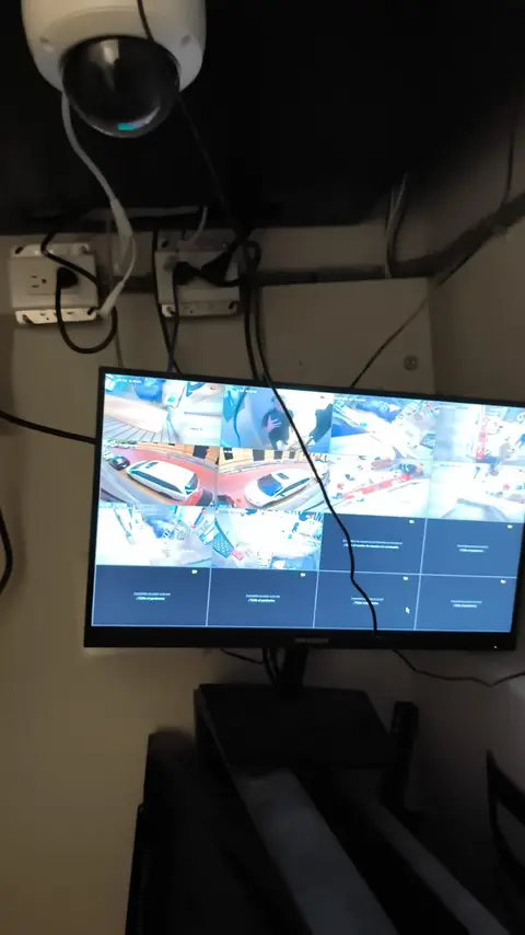 Cámara domo instalada en interior junto a un monitor con vista del estacionamiento