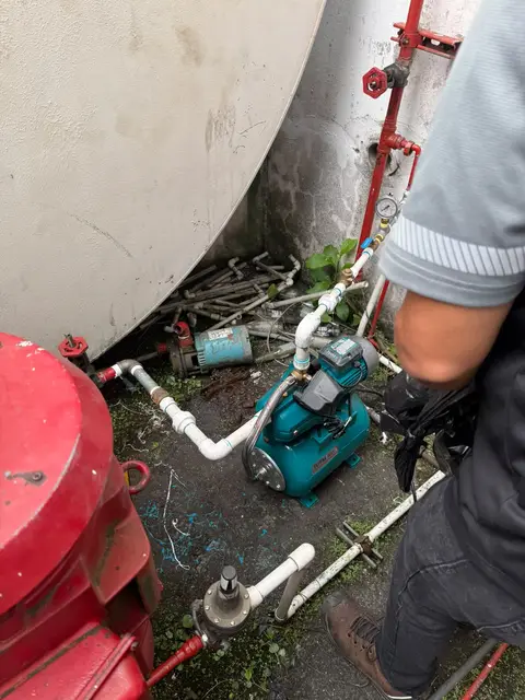 Técnico revisando la bomba de presión junto al tanque de agua contra incendios