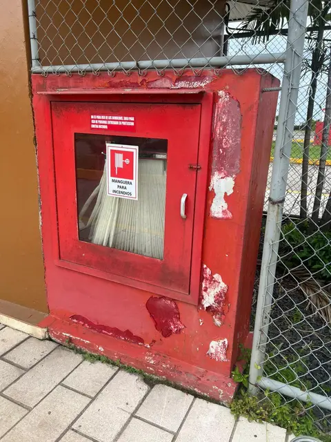 Gabinete de manguera contra incendios con pintura desgastada, en revisión de mantenimiento