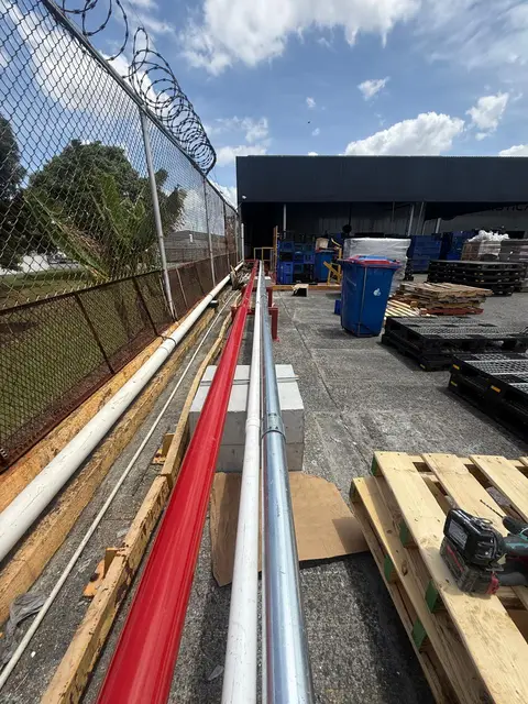 Tubería roja del sistema contra incendios instalada junto a la cerca perimetral de una bodega